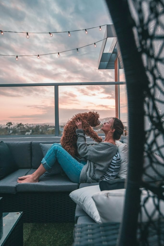 woman-holding-dog-while-sitting-on-sofa-jgvvefbtvq